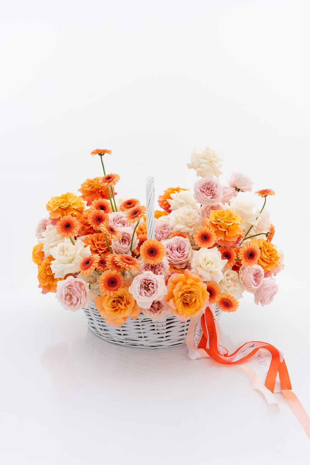 A vibrant basket of pink peony roses, gerberas, and white roses