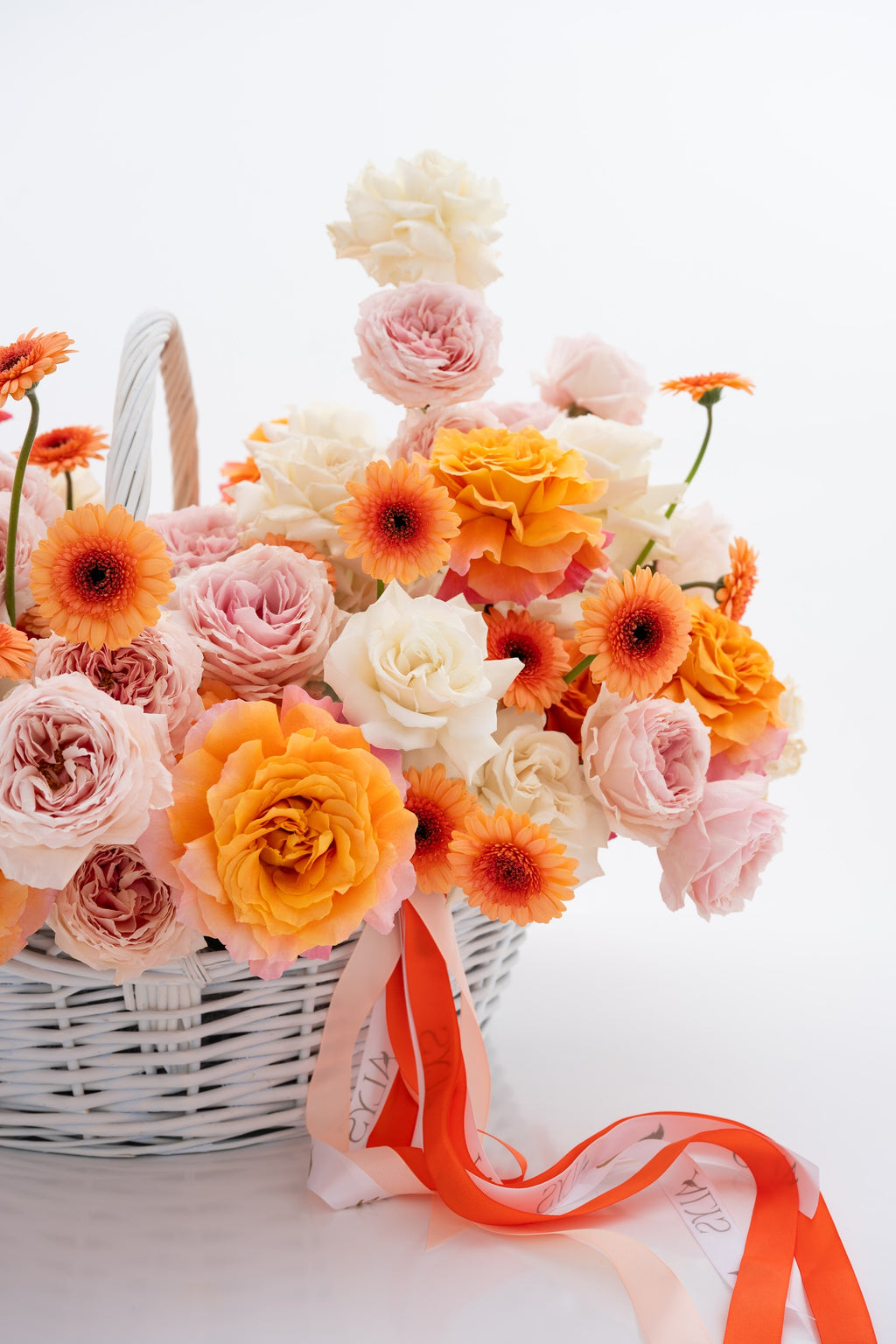 A vibrant basket of pink peony roses, gerberas, and white roses