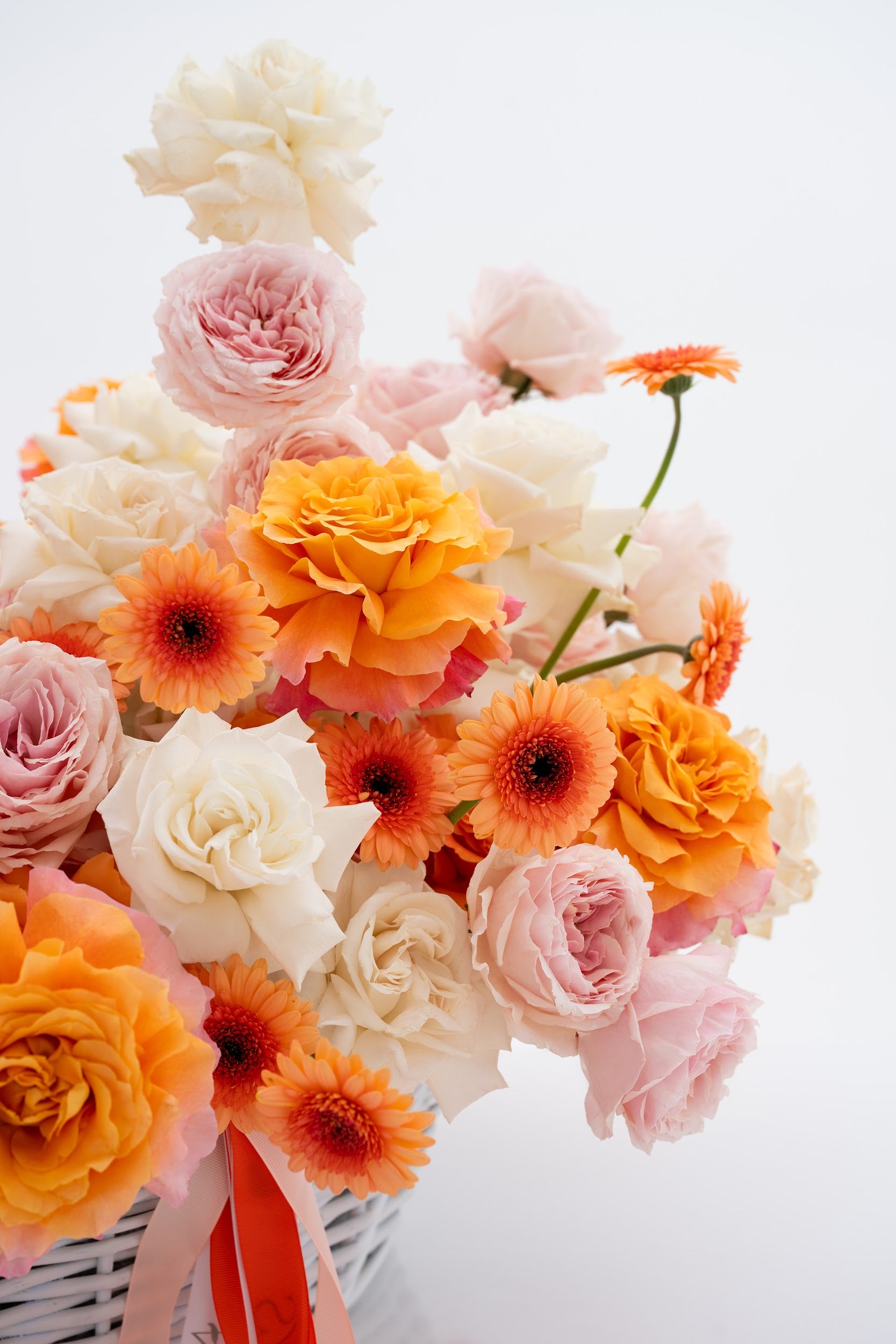 A vibrant basket of pink peony roses, gerberas, and white roses