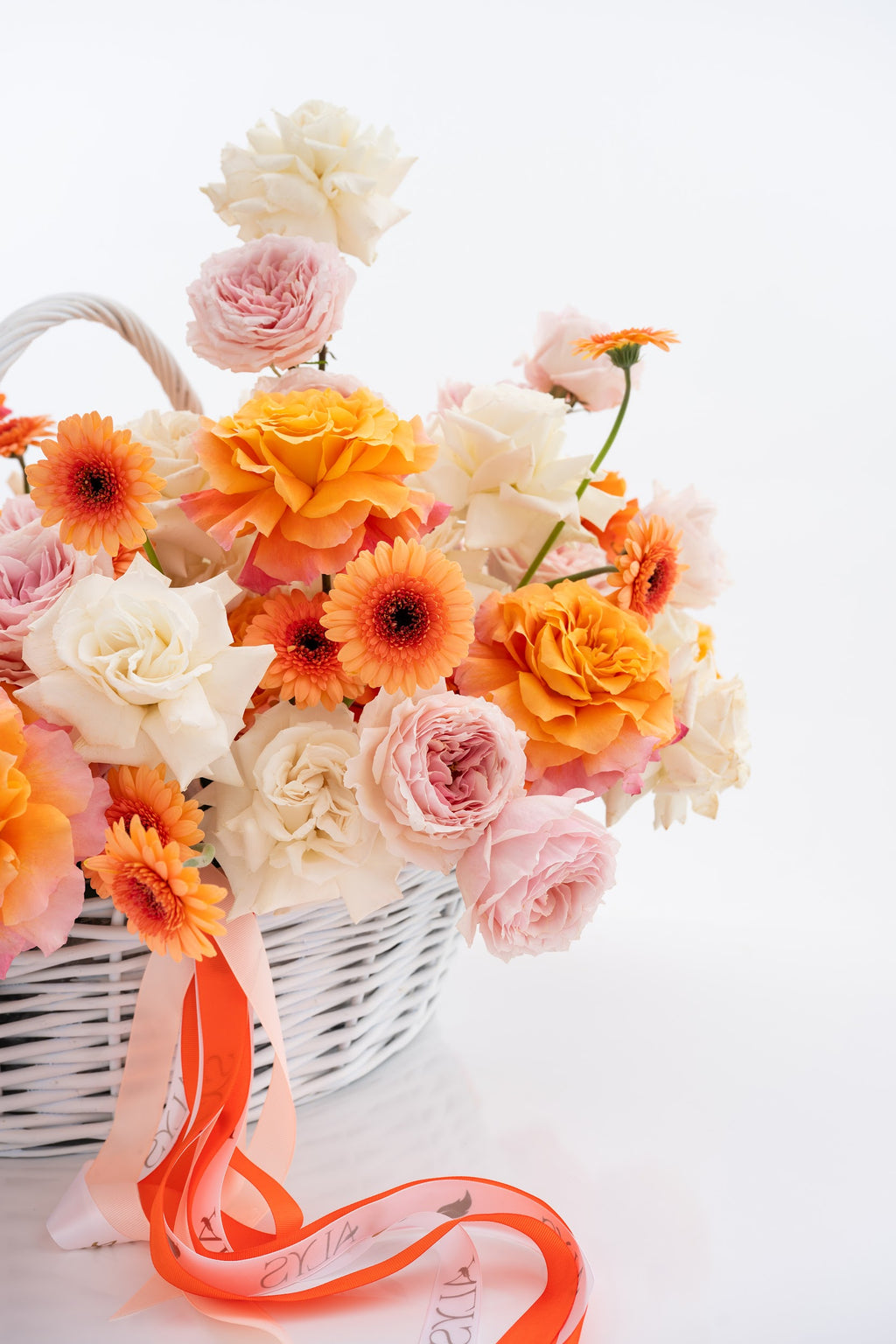 A vibrant basket of pink peony roses, gerberas, and white roses