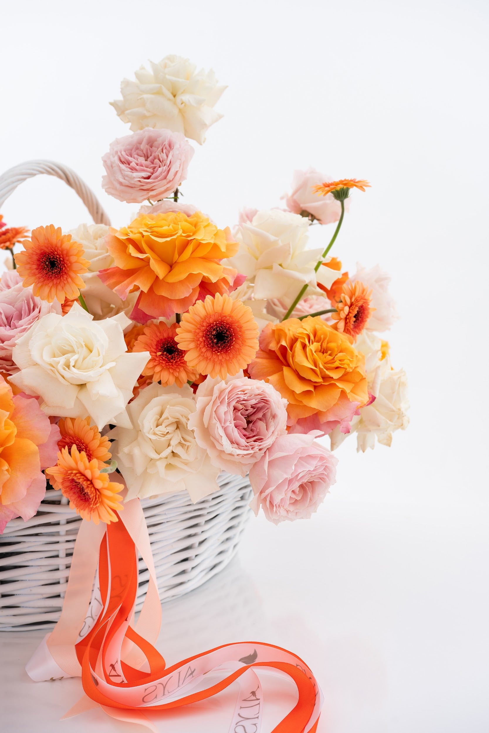 A vibrant basket of pink peony roses, gerberas, and white roses